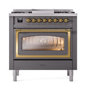 Matte graphite dual fuel gas range with brass-trimmed oven window glowing behind glass