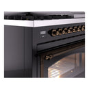 Close-up of glossy black control panel and oven window with bronze knob handles.