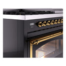 Brass control knobs and oven door handle on glossy black freestanding range, oven lit