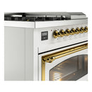 ILVE Nostalgie II range control panel with brass knobs and gold-trimmed oven door, white body