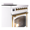 White induction range with brass trim, control knobs, and triple glass oven door