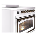 White induction range cooktop with bronze control knobs and oven with glass door