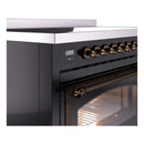 Close-up of bronze control knobs and digital display on a glossy black induction range.