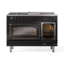 Glossy black dual fuel range with left oven open and right oven door ajar, brass handles