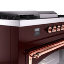 Burgundy range control display with copper knobs and stainless cooktop edge