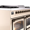 Antique white dual fuel range control panel with bronze knobs and a lit glass oven door