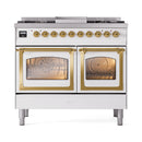 White dual fuel range with brass trim, triple-glass oven doors, and burner control panel.
