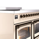 Antique white induction range control panel with bronze knobs above an oven door