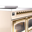 Antique white oven control area with brass knobs and arched brass oven handle