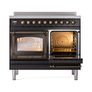 Glossy black induction range with bronze-trim door open, showing heated oven rack interior