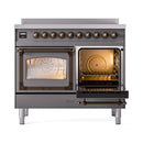 Matte graphite induction range with open left oven showing bronze-lit rack and knobs