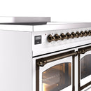Bronze control knobs and oven door handle on a white induction range